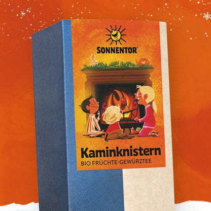 SONNENTOR Kaminknistern Früchtetee, Packung in winterlicher Szene